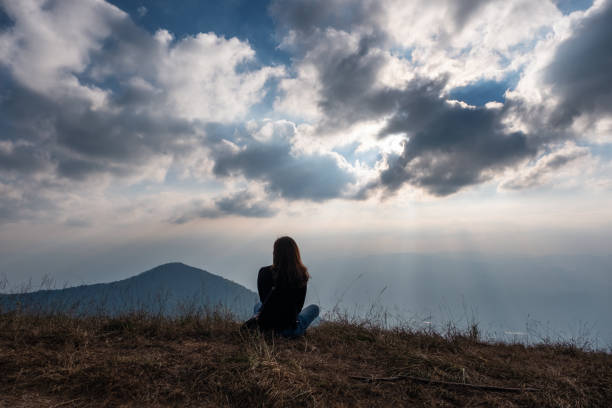 istock A woman sitting and watching sunset with mountains view 1094732042