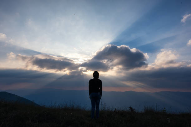 A woman standing and watching sunset with mountains view in the evening