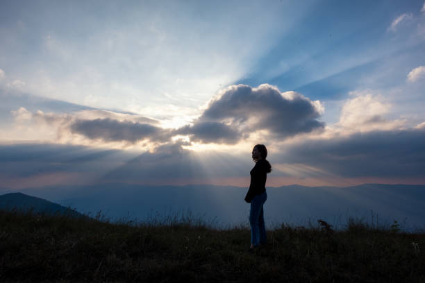 istock A woman standing and watching sunset with mountains view 1094732174