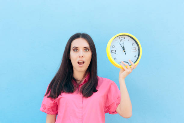 istock Cheerful Woman Holding a Clock on a Blue Background 1094733624
