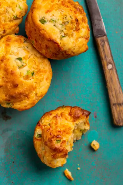 Jalapeno and cheddar cornbread muffins on vibrant colored rustic wood background.