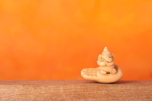 Happy smiling elephant clay sculpture on hand with space on blurred orange background