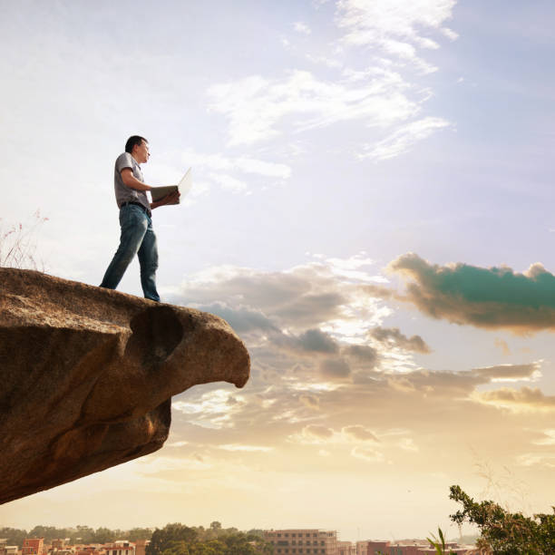 istock Man standing at the edge of a cliff using laptop 1094751380
