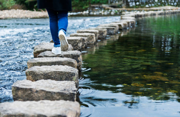 istock Woman crossing stepping stones on a river 1094755252