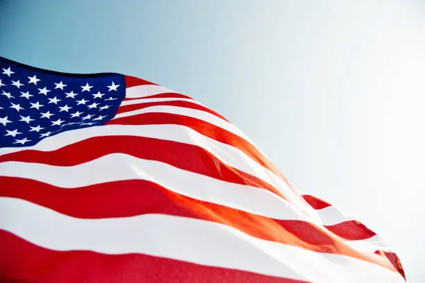 Close-up of American flag waving against blue sky.