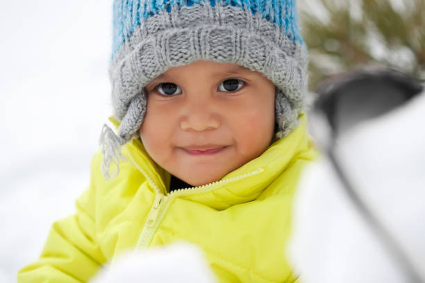 simpatico bambino latino sorridente mentre gioca sulla neve durante l'inverno e indossa un cappello a maglia. - garment snow little boys child foto e immagini stock