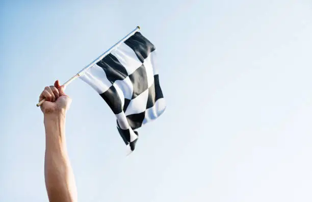 Man hand holding checkered flag in the wind.