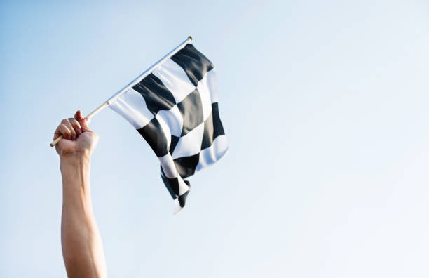 человек стороны проведения клетчатый флаг на ветру - checkered flag flag auto racing starting line стоковые фото и изображения