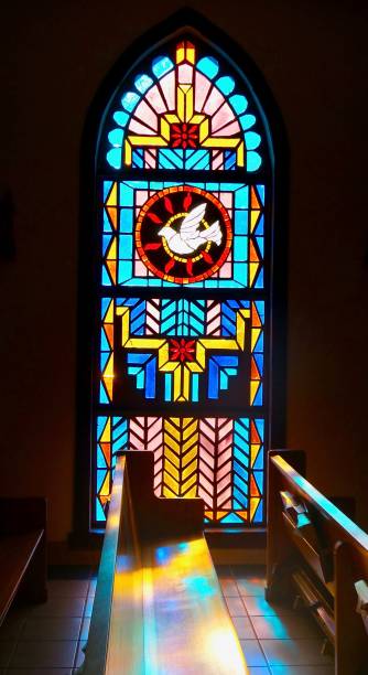 réflexions du vitrail du saint-esprit sur un banc d’église dans l’église catholique san ysidro à corrales, nouveau-mexique - banc déglise photos et images de collection