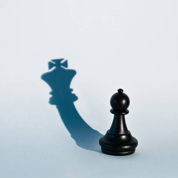 istock Black chess pawn with the shadow of a king 1094776360