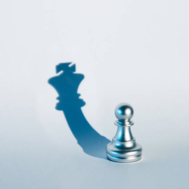 istock Silver chess pawn with the shadow of a king 1094776364