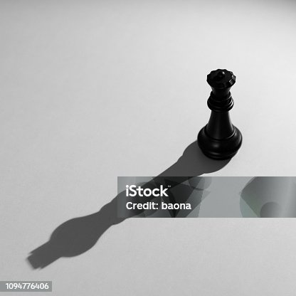 istock Black chess queen with the shadow of a king 1094776406