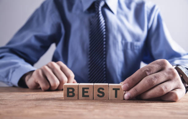 istock Businessman holding wooden cube with Best word. 1094776504