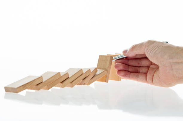 Man hand holding a pen stop domino effect.