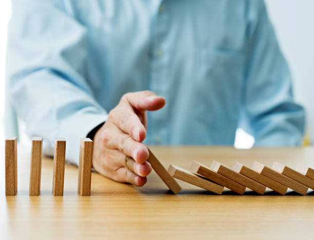 istock Businessman hand stopping falling blocks on table 1094782838