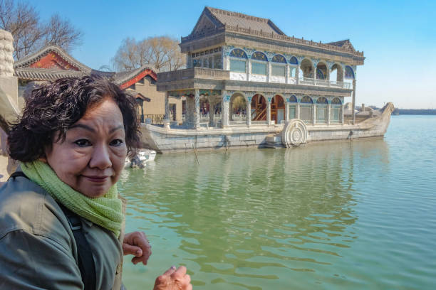 retrato de asia senior femenino con barco de piedra de mármol en el palacio de verano de pekín - traditional culture dragon old asian culture fotografías e imágenes de stock