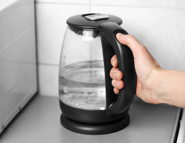 istock Hand holding a glass teapot with black handle. Close up 1094800970
