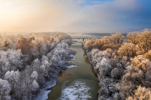 Budapest, Hungary - Frosted trees at sunrise with railway bridge and island at winter time