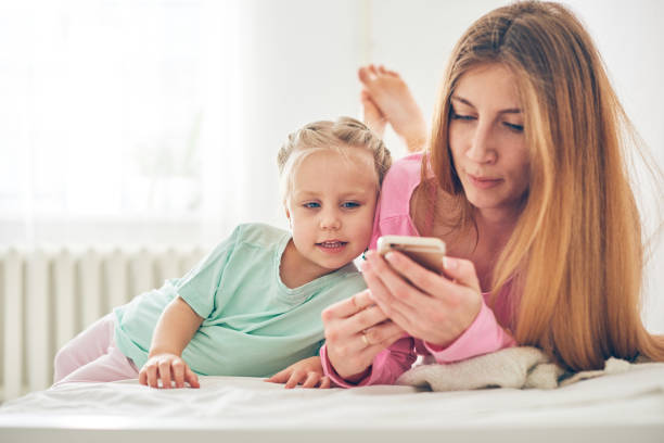 istock Mother and daughter using phone in bed 1094806852