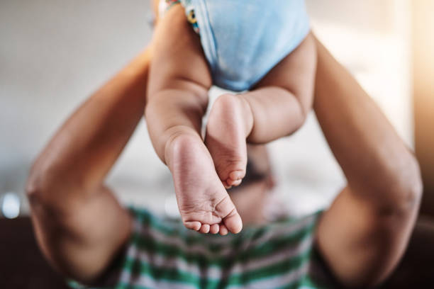 We are blasting off! Shot of an unrecognizable little boy being lifted up by his dad while being seated on a sofa at home during the day dad and baby stock pictures, royalty-free photos & images