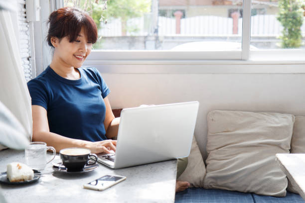istock Asian young woman holding credit card mockup and using laptop computer while sitting in cafe. Online shopping concept. Copy space. Selective focus. 1094814092