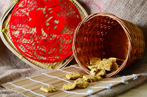 Chinese new year homemade cookies with sesame seeds, on bamboo stick , on sackcloth background