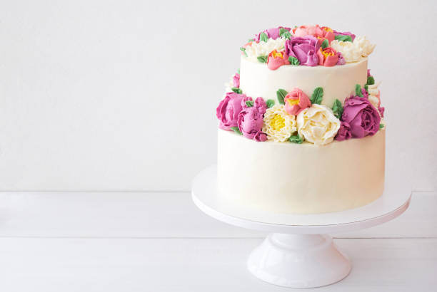 istock Two-tiered white wedding cake decorated with color cream flowers 1094821236
