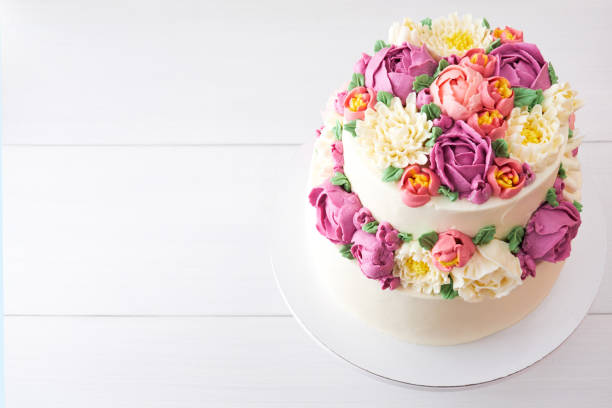 istock Two-tiered white wedding cake decorated with color cream flowers 1094821270