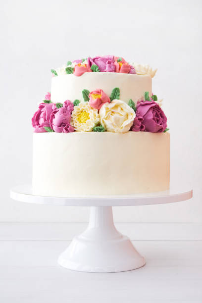 istock Two-tiered white wedding cake decorated with color cream flowers 1094822310
