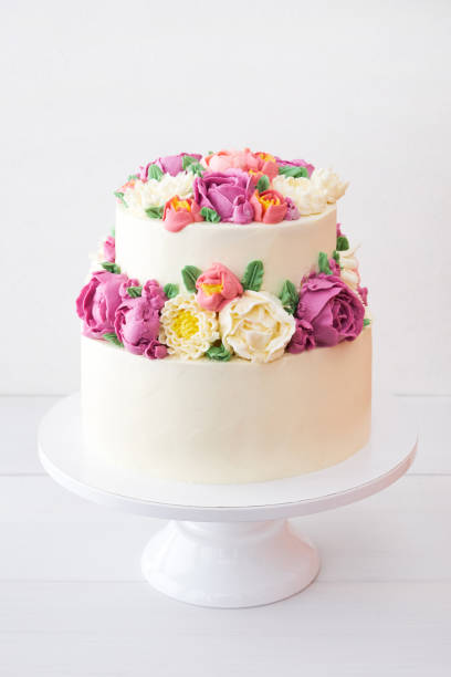 istock Two-tiered white wedding cake decorated with color cream flowers 1094822320
