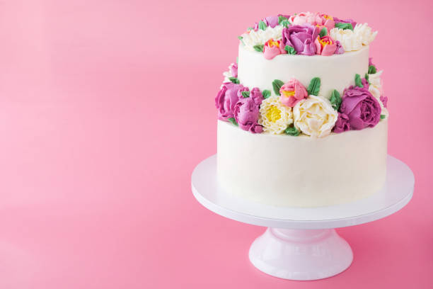 istock Two-tiered white wedding cake decorated with color cream flowers 1094822436