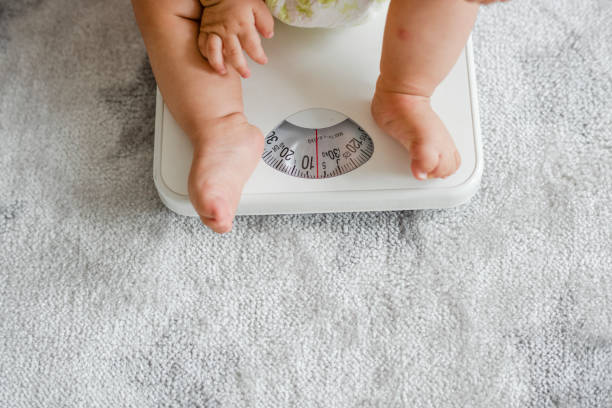 closeup of a baby&#39;s legs on a weighing scale - instrument of weight imagens e fotografias de stock
