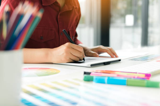 istock Freelance creative designers working on desk using digital graphic tablet and drawing with pen in modern home office. 1094824104