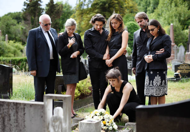 rodzina składająca kwiaty na grobie - funeral zdjęcia i obrazy z banku zdjęć