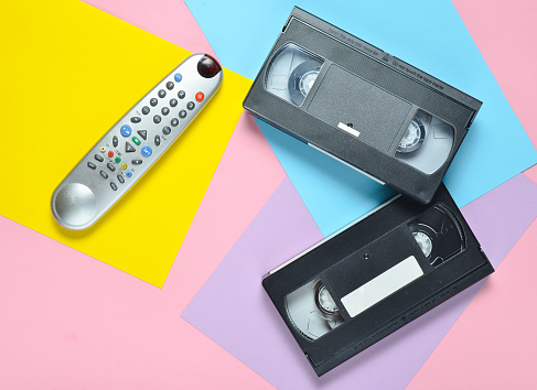 Mando a distancia, video cassettes sobre un fondo color pastel. Tecnología de entretenimiento retro de los años 80. Tendencia del minimalismo. Vista superior. photo