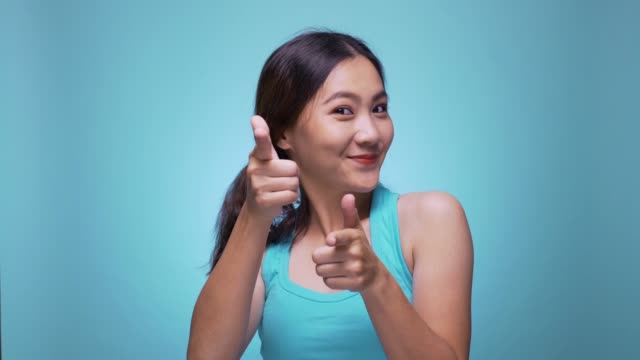 Woman pointing to camera on isolated blue background 4k