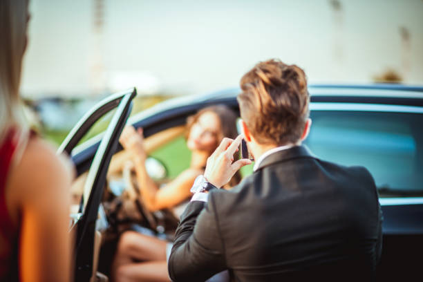 задний вид богатого бизнесмена, фотографируя женщину, выбирая роскошный автомобиль со смартфоном - luxury car women smart phone стоковые фото и изображения