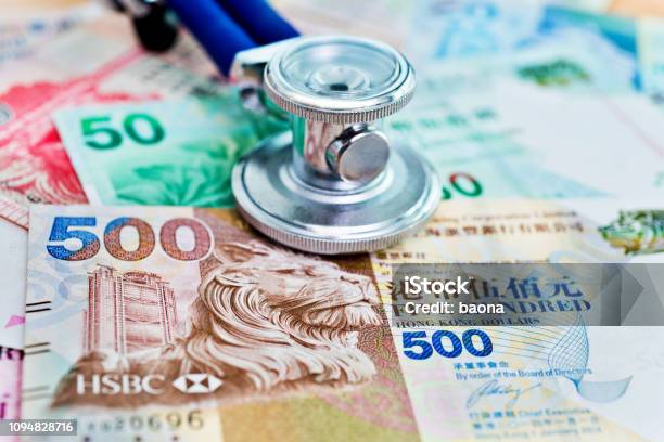 Stethoscope On Top Of Hong Kong Dollars Stock Photo - Download Image Now - Analyzing, Business, Business Finance and Industry