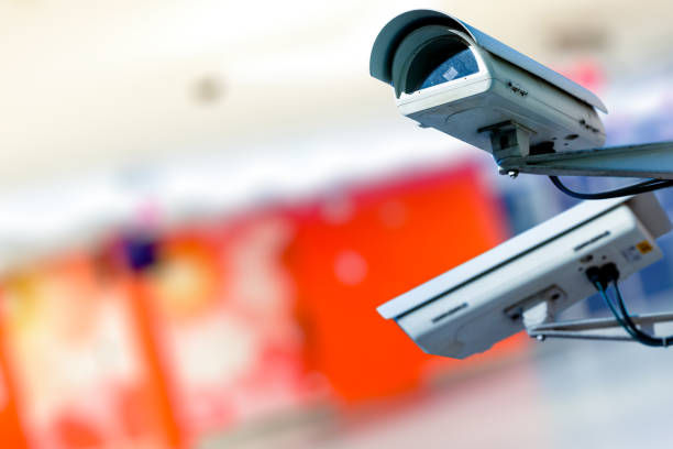 Modern CCTV camera on a wall. with blurred coloreful background. Modern CCTV camera on a wall. Concept of surveillance and monitoring. cctv camera overlay stock pictures, royalty-free photos & images