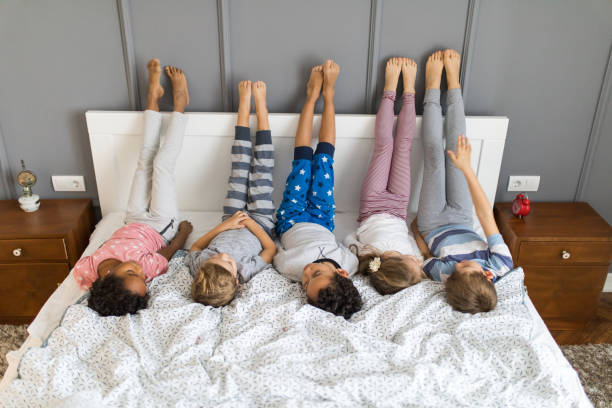 istock Group of cute kids lying on a bed with their legs up. 1094830290