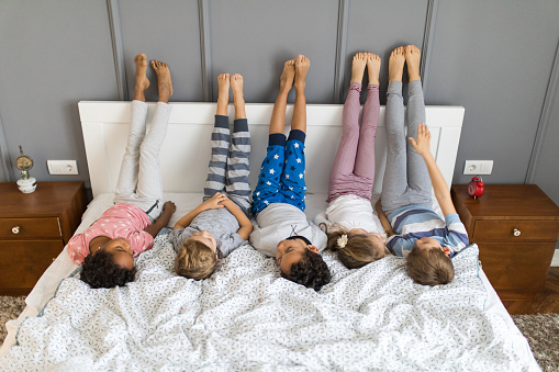 Little friends lying on a bed in bedroom with their feet up on the wall.
