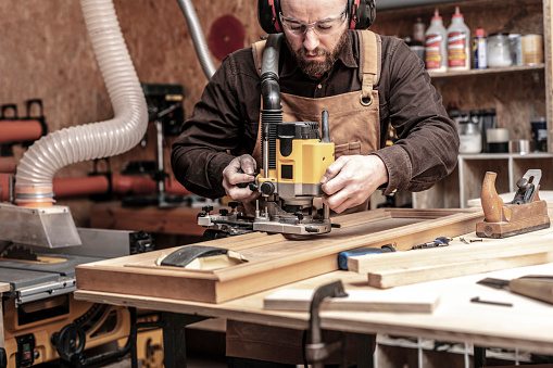 caucasian man using a router in his workshop