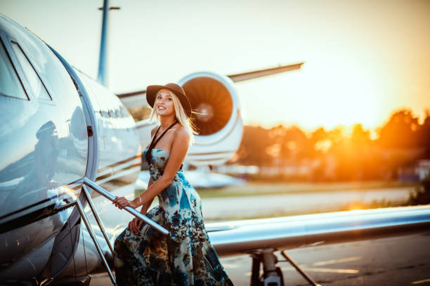 Beautiful blonde girl boarding a private airplane at sunset Glamorous blonde woman climbing aboard a private jet at sunset. airport runway photos stock pictures, royalty-free photos & images