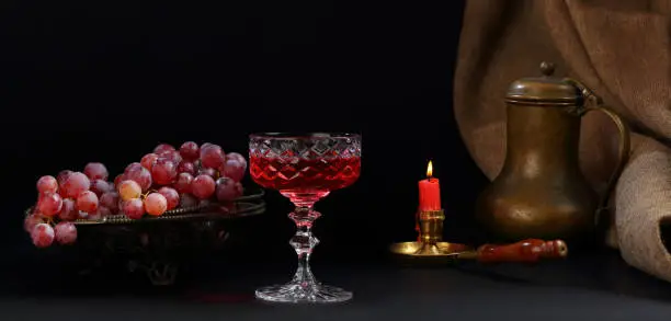 Photo of Still life with a vase of grapes, a jug, a burning candle and a glass of wine