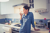 Woman drinking milk in kitchen.