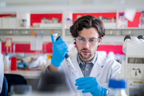 исследователь с использованием автоматической пипетки в лаборатории - genetic research men chemical protective glove стоковые фото и изображения