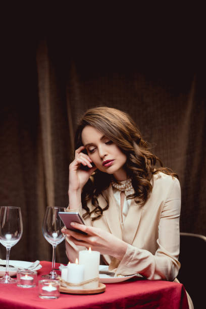 istock beautiful pensive woman sitting at table and using smartphone in restaurant 1094846934
