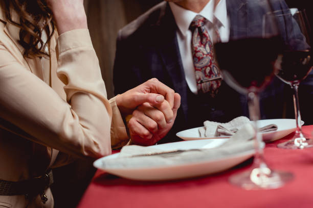 istock partial view of couple holding hands while having romantic date in restaurant 1094847150