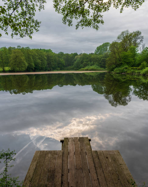 Silhouette of jetty with dark cloudscape after rain at lake Steinhuder Meer, Lower Saxony, Germany