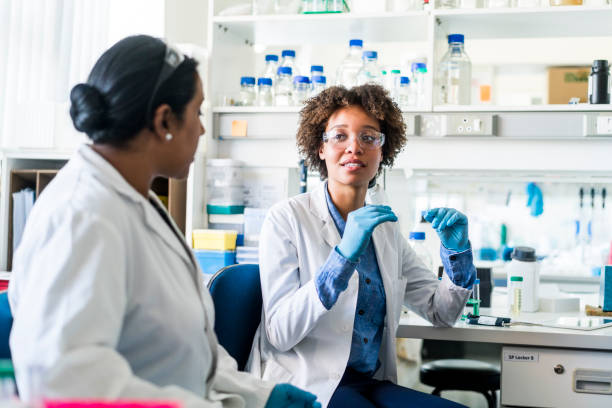 young scientist discussing with colleague in lab - teamwork medical research science women imagens e fotografias de stock